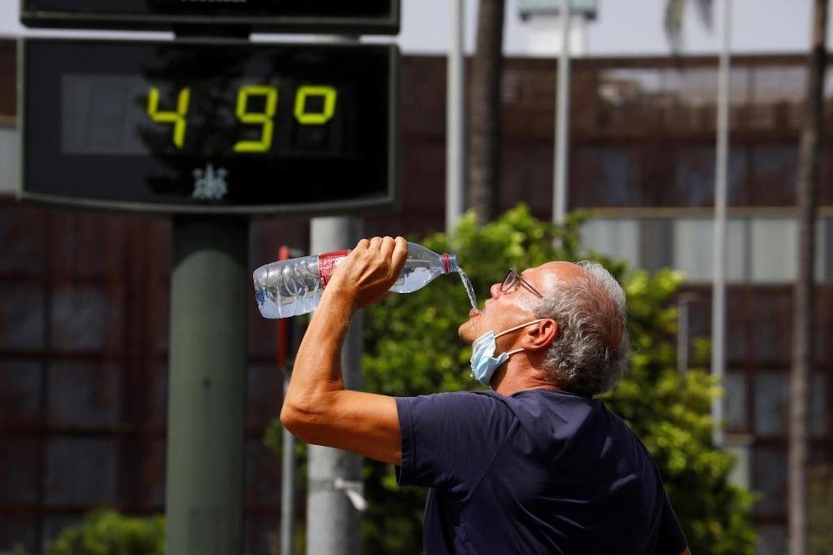 Un hombre bebe agua en plena ola de calor.