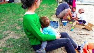 Un madre amanta a su bebé, en un parque.