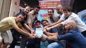 Los miembros de La Pegatina rodean al dibujante Mr. Ed y al guionista Lluc Silvestre (derecha), mordiendo el cómic del aniversario.