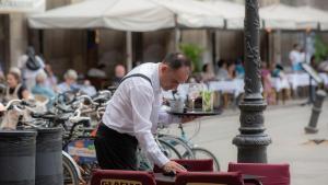 Un camarero limpia una mesa en una terraza.