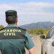 Archivo - Un agente de la Guardia Civil junto a un vehículo en una carretera.  (Foto de archivo).