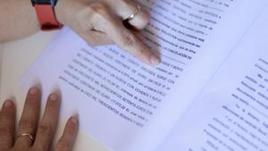 Archivo - Una mujer señala una escritura de compraventa de vivienda realizada con una hipoteca
