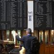 Un hombre señala los paneles de valores del IBEX 35 en el Palacio de la Bolsa de Madrid