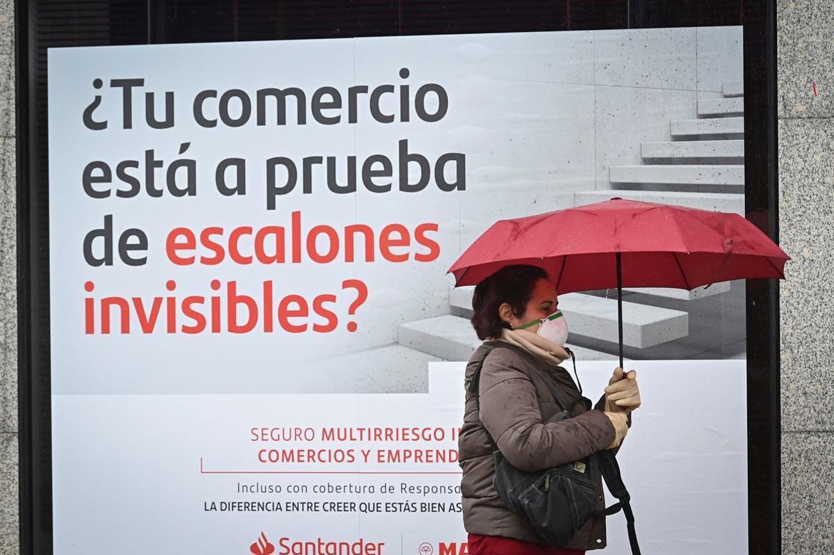 Una mujer camina junto a una sucursal del Banco Santander.