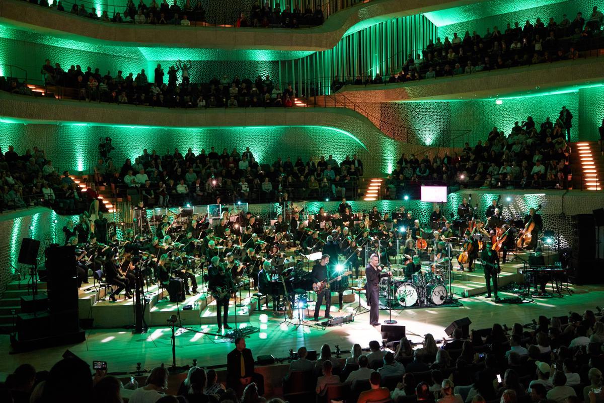 El cantante británico Robbie Williams y los músicos de la Nueva Orquesta Filarmónica de Fráncfort actúan en el escenario durante un concierto en directo en la Gran Sala de la Elbphilharmonie (Archivo)