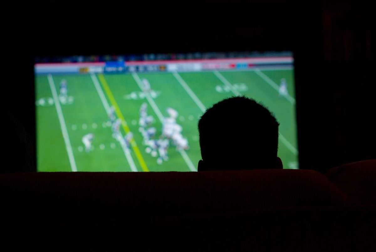 Un hombre ve en la televisión un partido de la NFL. Un hombre ve en la televisión un partido de la NFL.