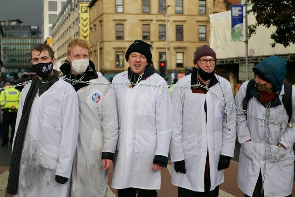 Miembros de Scientist Rebellion encadenados en el puente King George V de Glasgow, que originó en noviembre de 2021 el primer arresto masivo de científicos por la crisis climática.